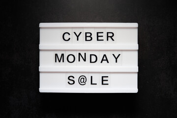 Cyber monday sale is written on a light box. The light box is on a black background. Top view photography.