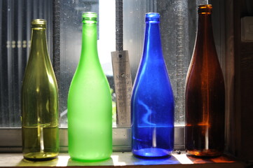 Empty and transparent glass bottles standing in a row, green, blue and brown