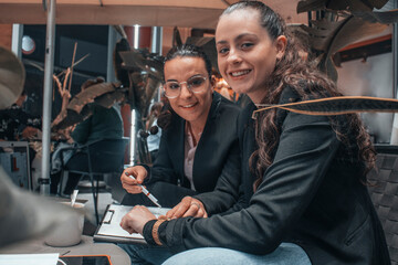 Chicas empresarias sonrientes trabajando en equipo escribiendo ideas y planteamientos en su tablet...