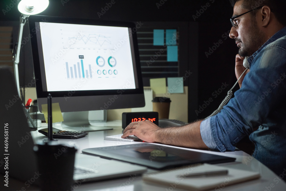 Wall mural asian man concentrating on working in the office at night