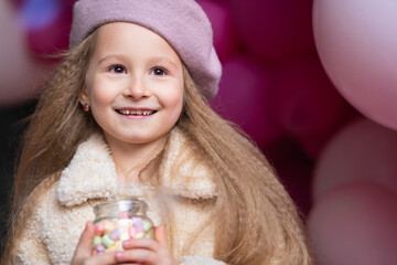 happy smiling, laughing little girl in beret playing with pink, purple balloons, outdoors. childrens emotions. beautiful child on holiday. Kid birthday party concept