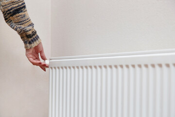 Woman adjusting thermostat radiator valve.