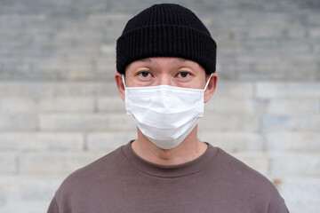 Portrait of asian man in a medical mask close-up on gray background.