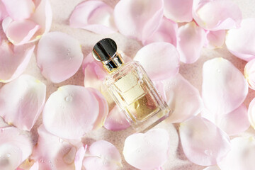 Glass, empty perfume bottle on  background with roses petals. Concept of delicate feminine floral scent of rose. 