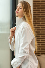 Beautiful young woman in sweater looking through the window