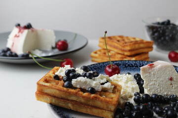 delicious healthy breakfast. Belgian soft waffles with curd cheese cream and blueberry cherries lie white blue plate view from the top. Delicious still life