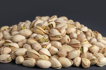 Pile of pistachios in the peel close-up on a dark background.