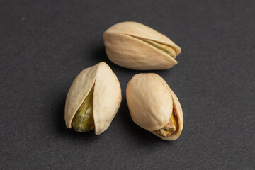 Peeled and unpeeled pistachios on dark background