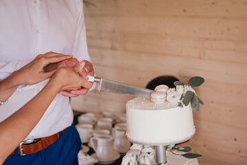 People cutting delicious white wedding cake with macaroons
