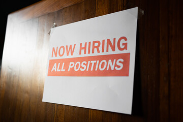 Now hiring sign on the wall