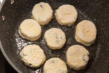 Eight Raw uncooked cottage cheese pancakes just put to the pan with old being prepared