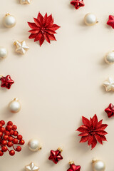 Beige vertical Christmas background with balls, stars, red flowers decoration. Christmas frame. Flat lay, top view, copy space.