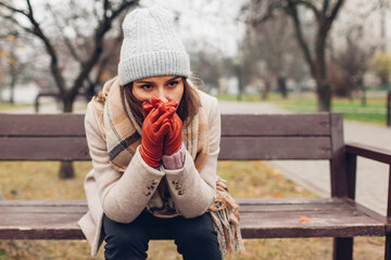 Depression. Woman in trouble sitting on bench in autumn park covering face with hands. Mental health