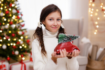 portrait of cute girl with toy in bright decorated living room with Christmas tree