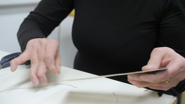 handicapped physically disabled person with crooked fingers cuts thread with scissors