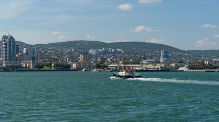 Sea Pilot 'Adis' is sailing in turquoise water along Tsemes bay. Close-up of white work boat 'Adis' on Novorossiysk Commercial Sea Port background.  Novorossiysk, Russia - September 15, 2021