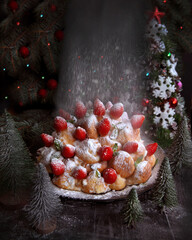 Delicious Christmas cake made of profiteroles with strawberries sprinkled with powdered sugar. Christmas Holiday Recipes - 469666761