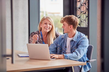 Male University Or College Student With Laptop Having Individual Meeting With Tutor