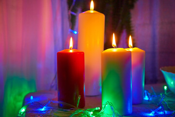 Candles with lights in a dark room and illuminated with garlands for Christmas or New Year