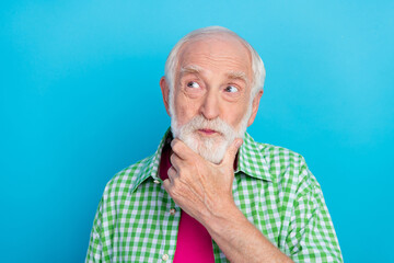 Photo of thoughtful smart minded old granddad look empty space hold hand chin isolated on blue...