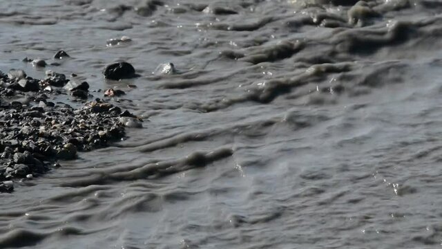 river of mud and water rushes towards the sea after intersting rains