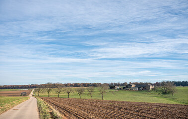 Fototapeta na wymiar plowed field with meadow and old farm in belgian ardennes near namur