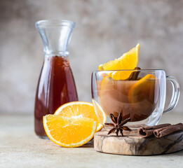 Autumn or winter hot tea or punch with orange and spices in a glass cup. Hot spicy beverage. Seasonal mulled drink.