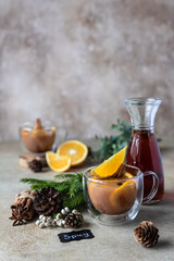 Autumn or winter hot tea or punch with orange and spices in a glass cup. Hot spicy beverage. Seasonal mulled drink.