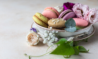 Various types of colorful macarons or macaroons decorated with flowers on light background. Traditional french almond dessert with sweet filling.