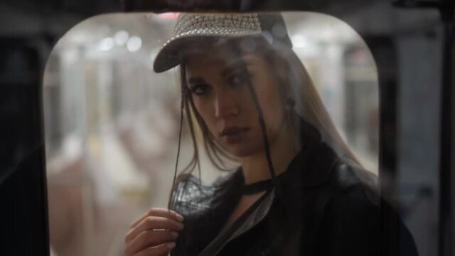 Fashion model poses through the glass on camera rides in a subway car. Beautiful girl looking into the reflection of the glass of the subway car. FHD video. Kyiv Metro