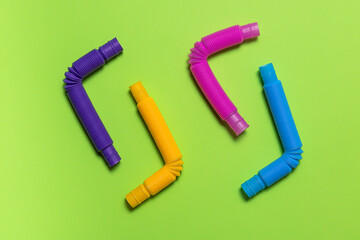 Angle bended bright pop tube toys on green paper background
