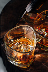 a cut of a tree, cut with a hatchet, there are two glasses of whiskey and ice on it. rest concept after a hard day at work. whiskey and wood