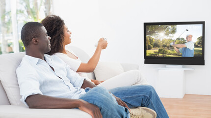 Rear view of african american couple sitting at home together watching golf on tv