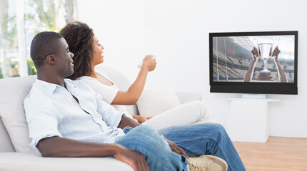 Rear view of african american couple sitting at home together watching sport event on tv