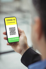 Man holding smartphone with covid 19 vaccine passport