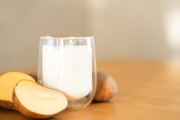 Potato milk photo on wooden background. Glass of alternative milk. Plant based vegetarian beverage....
