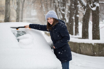 Woman removing snow from car windshield