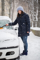 Woman removing snow from car windshield