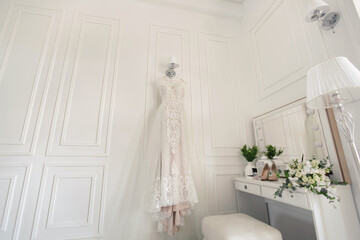 Fototapeta na wymiar Elegant wedding white dress hanging on a wall during a wedding preparation. Bride's morning. Before ceremony