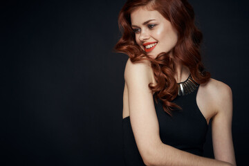 Naklejka premium attractive red-haired woman in a black dress hairstyle dark background