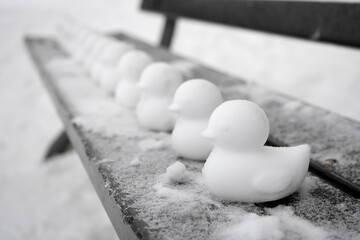 Fototapeta na wymiar Schneefiguren und Eisfiguren als Enten oder Küken im frostigen Winter auf einer schneebedeckten Parkbank