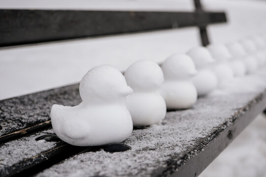 Schneefiguren und Eisfiguren als Enten oder Küken im frostigen Winter auf einer schneebedeckten Parkbank