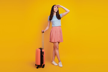 Full length photo of young attractive woman happy positive smile bag suitcase travel fly abroad look isolated over yellow color background