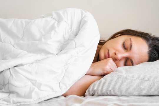 Young millennial woman sleeping covered with blanket. Cold winter. No heating at home. Loud snoring. Sweet dreams. Circadian cycles.