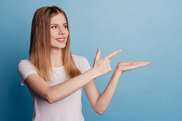 Photo of dreamy confident lady hold palm presenting empty space indicate forefinger on blue color background