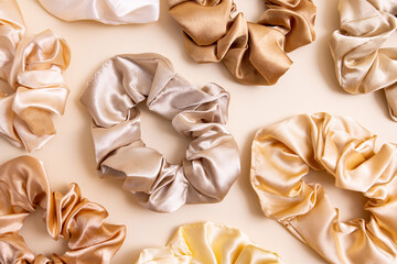 Collection of trendy silk elastic bands scrunchies on beige background. Diy accessories and...