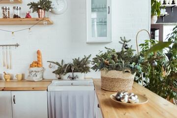 Stylish white kitchen in decor, Scandinavian trendy style. An eco-friendly wooden table, Christmas tree branch. New year template, card web