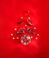 creative Christmas tree in the form of pomegranates against a red background. Unusual combination of usual things.Copy space