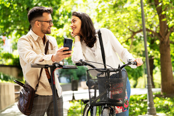 Happy funny couple with bicycle in the park. Loving couple enjoying together outdoors..