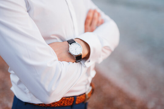 Man in a white shirt with a watch on his wrist crossed his arms over his chest. Close-up